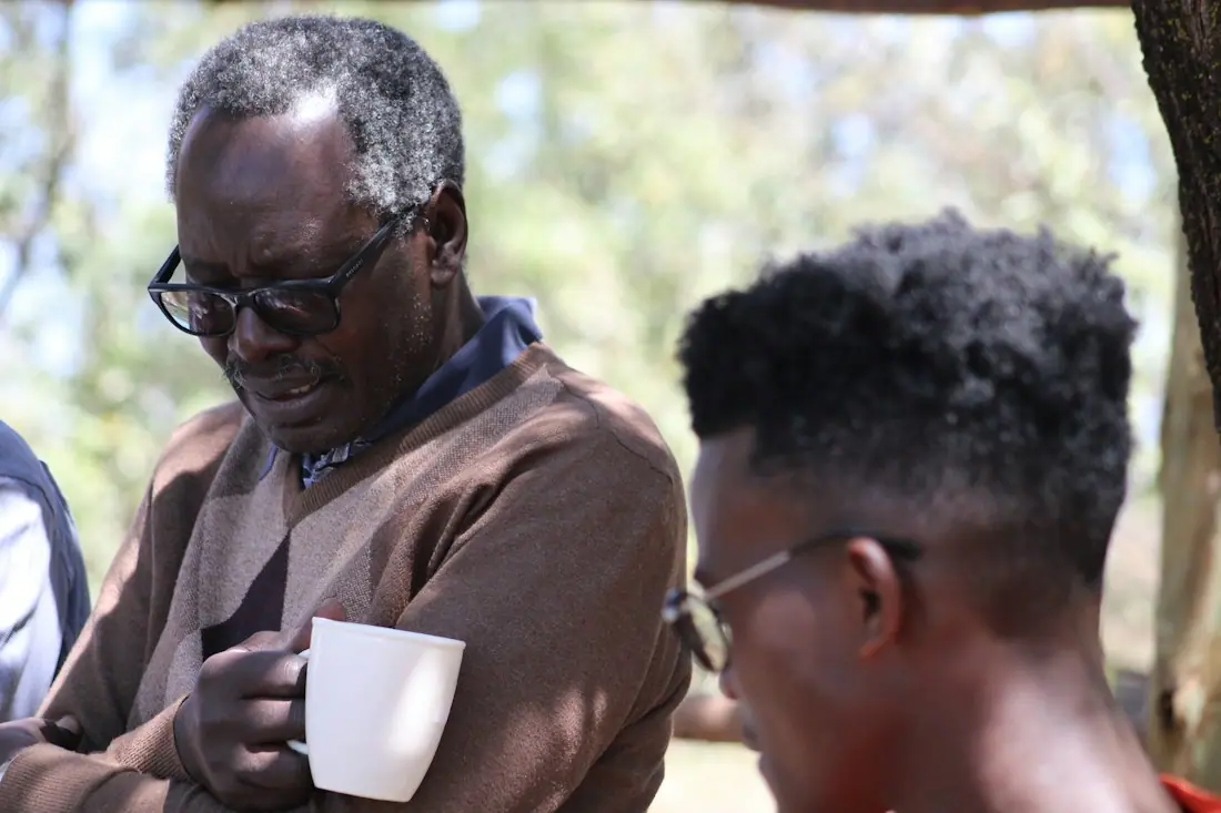 An older man talking with a younger man over coffee